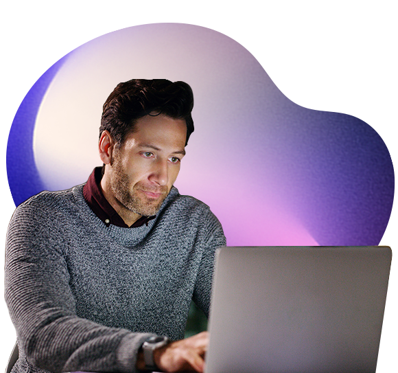 A man wearing a grey jumper works intently on a laptop