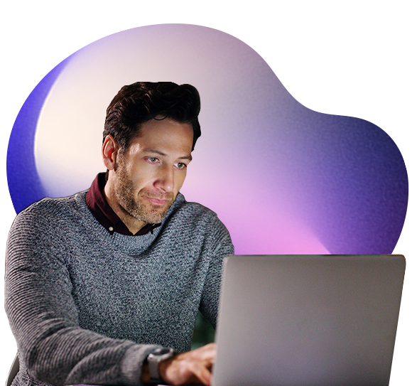 A man wearing a grey jumper works intently on a laptop