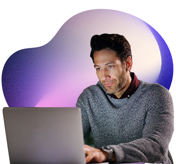 A man wearing a grey jumper works intently on a laptop
