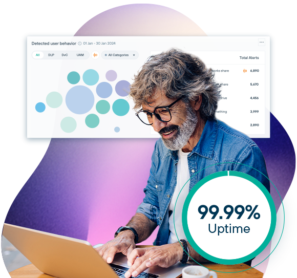 A grey-haired, bespectacled man looks happy as he works on a laptop.
