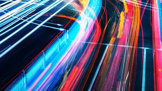 Streaks of light show the movement of traffic in the dark at a busy road junction