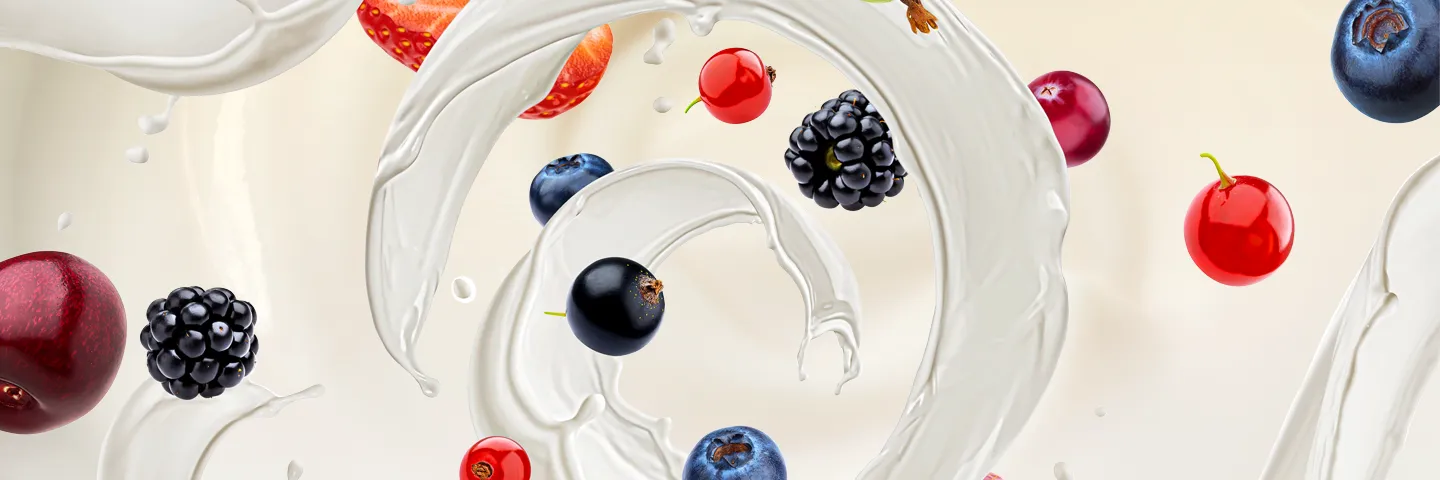 Various pieces of fruit and berries fall into a swirl of yoghurt