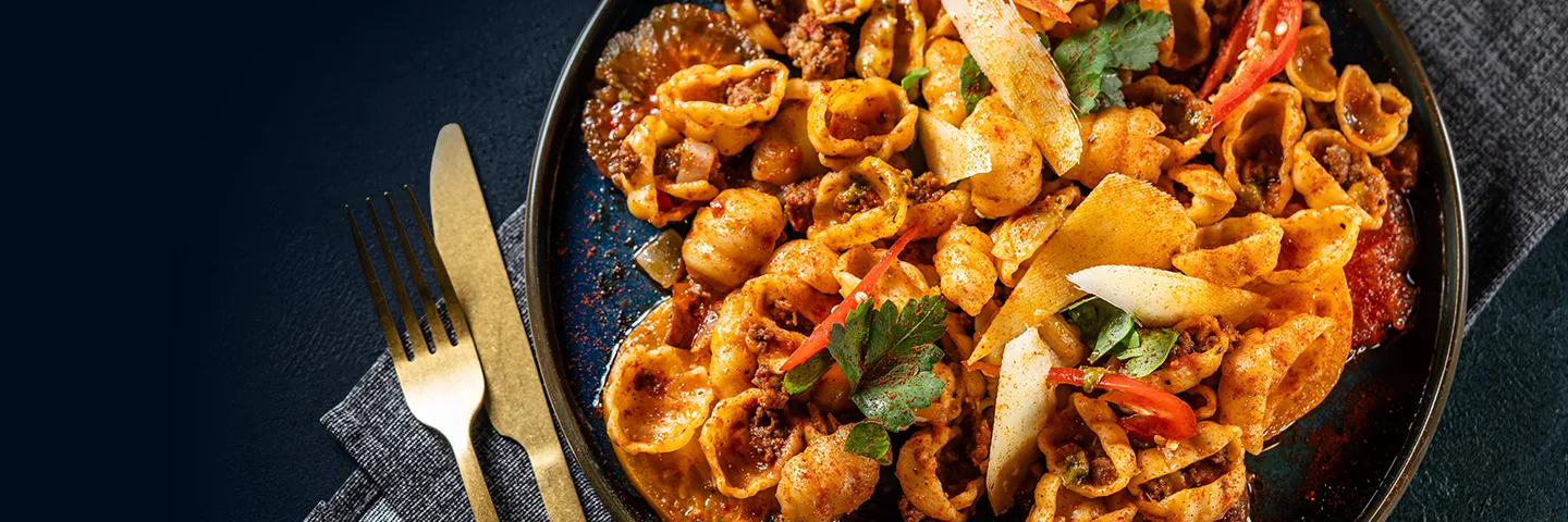 A place setting with a plate of delicious looking pasta and sauce.
